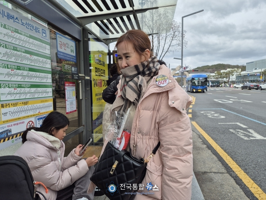 부정선거 OUT의 뺏지를 단 시민이 버스정류장에서 버스를 기다리고 있다 / 김경옥 기자