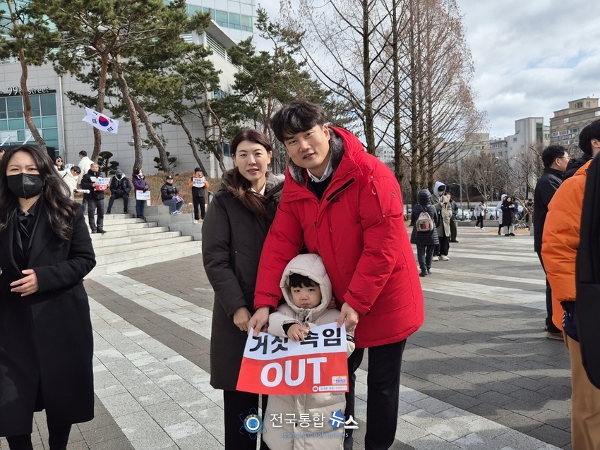 자녀와 함께 참석하여 설명하고 있는 2030부부가 거짓속임 OUT의 피켓을 들고 포즈를 취하고 있다 / 김경옥 기자