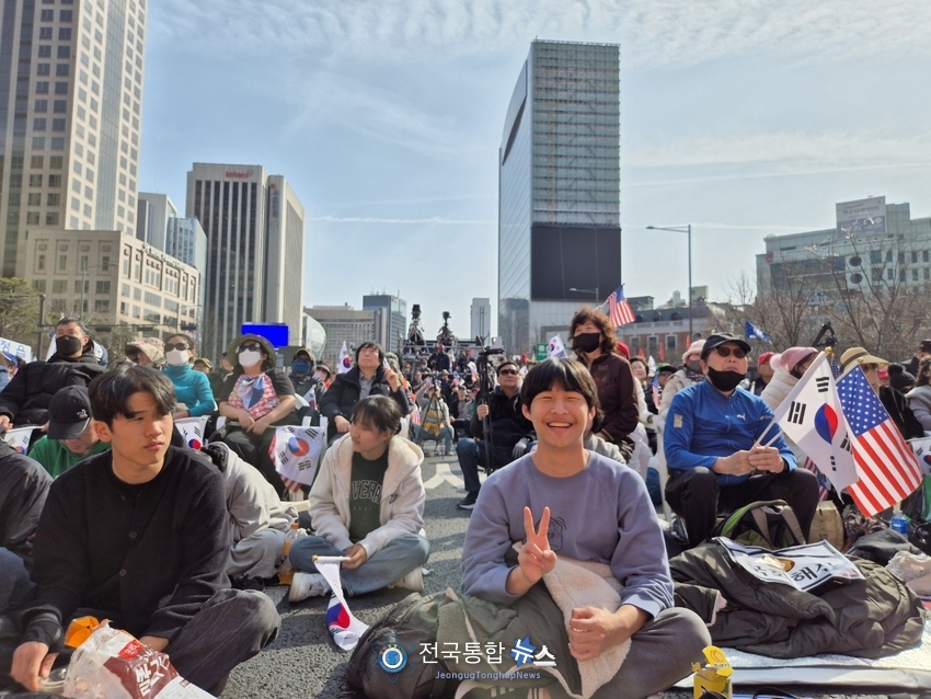 집회장 맨 앞 바닥에 앉아 연설을 듣고 있는 2030세대 젊은이들과 승리의 빅토리의 V와 함께 환하게 웃고 있다 / 김경옥 기자