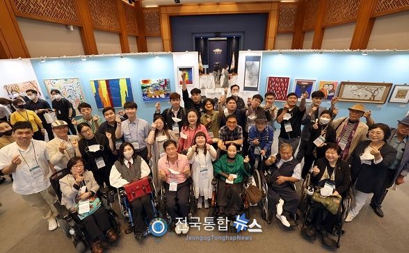 8월 31일 서울 종로구 청와대 춘추관에서 개막한 장애예술인 특별전 ‘국민 속으로 어울림 속으로’에서 발달·지체·청각 장애에도 활발히 작품 활동을 해온 참여 작가들이 손하트를 그리며 기념촬영 하고 있는 모습. (사진=문화체육관광부)